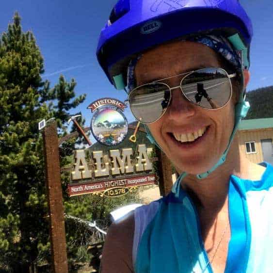 April next to the Alma sign in Alma, Colorado after mountain biking from Fairplay to Alma