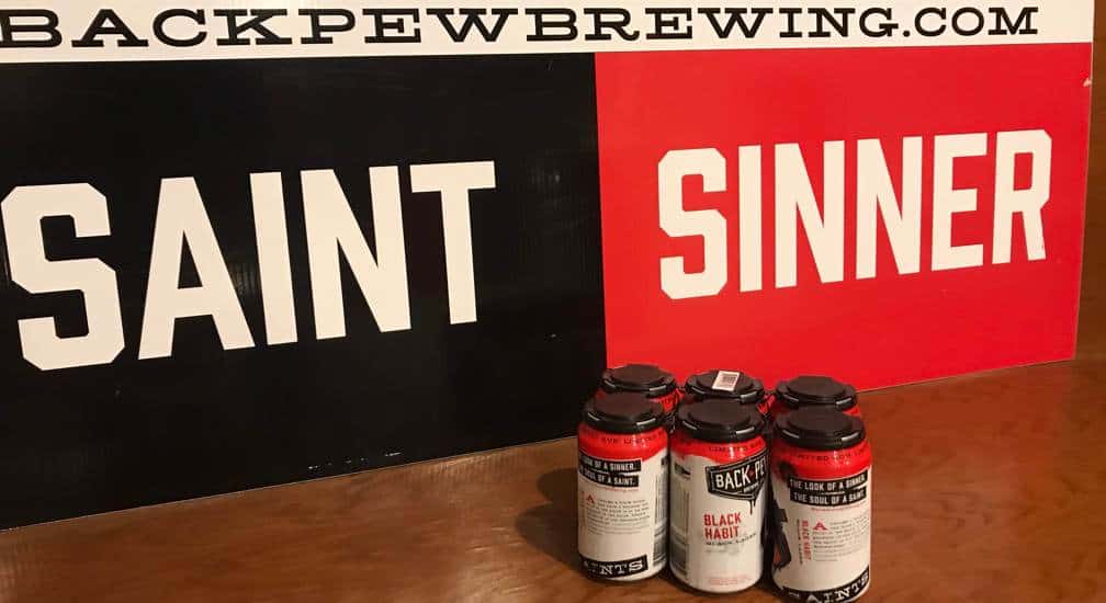 six pack of beer on a church pew with Saint and Sinner sign at Back Pew Brewing