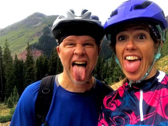 Kenny and April in they mountain biking helmets sticking out their tongues while overlooking a mountain pass near Clear Lake near Silverton Colorado