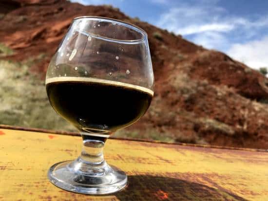 Ten Sleep Brewing Company Porter in a glass on an old truck with a view of the mountains