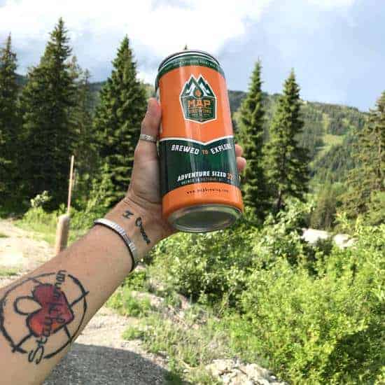 can of MAP beer being held in April's hand in front of scenic mountains and greenery