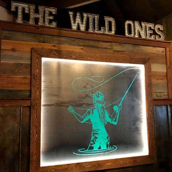 The Wild Ones sign with Jordan's mom fly fishing logo at Sacred Waters Brewing Co in Kalispell Montana