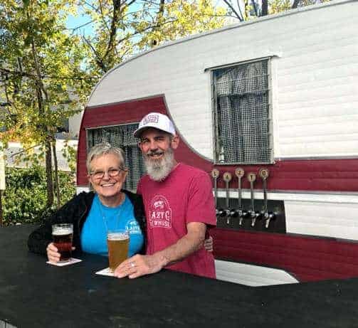 Jim and Jean-Marie posing with beer in front of trailer at LazyG Brewhouse in Prescott Arizona