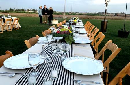 empty shared table beautifully set with dishes and glassware for the sunset dinner on the ranch in yuma arizona