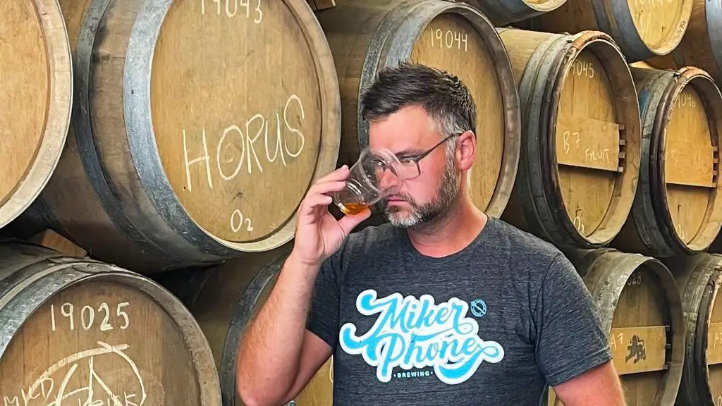 Mike at Mikerphone smelling beer in front of barrels Illinois cover