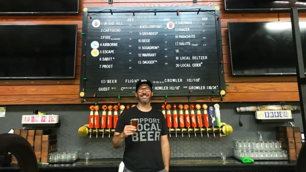 Adam Mills holding beer behind bar Cartridge Brewing Ohio