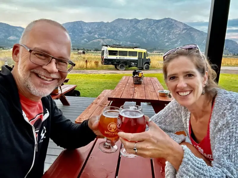 Ken and April cheers on patio with bus Melvin Brewing Alpine Wyoming